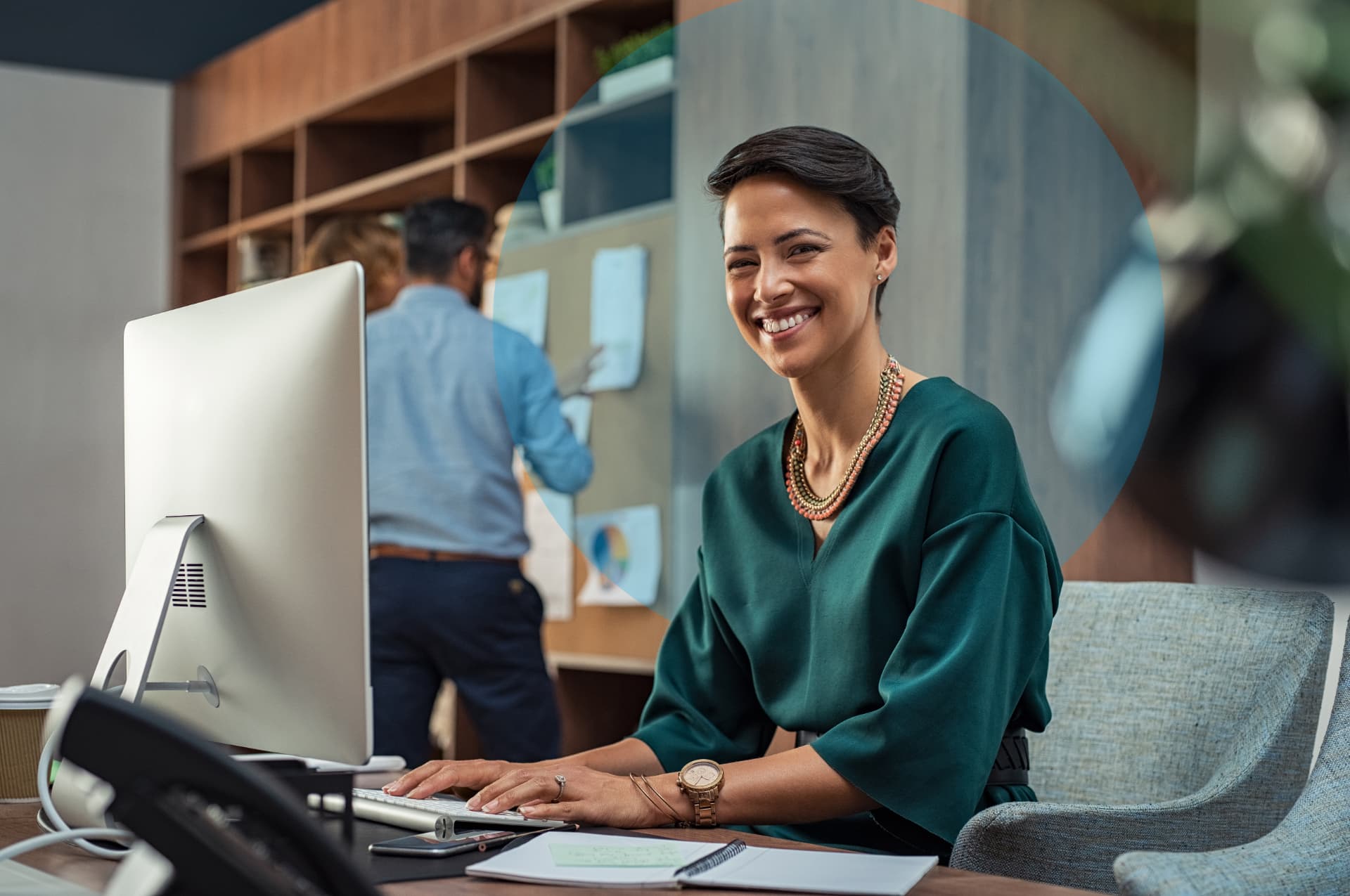 A woman smiling at the camera while working at her desk in a bright office